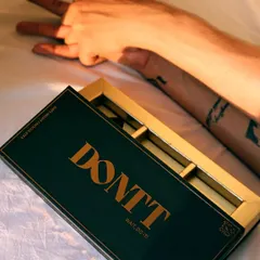 An artistic, top-down shot that combines the product with a human element. The focus on the hands and the empty box tells a story of indulgence.