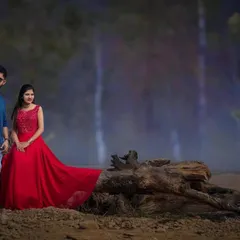 A stylish pre-wedding portrait with the couple posed against a dramatic, moody backdrop. The bride's flowing red gown adds a vibrant pop of color to this cinematic shot.