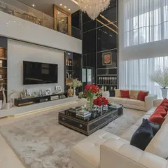 This grand, double-height living room showcases a modern luxury interior design. A large, comfortable sectional sofa faces a sleek, low-profile media console, creating an inviting space for relaxation and socializing in a high-end residential setting.