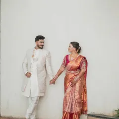 A beautiful wedding day portrait of the couple. The bride's traditional Maharashtrian look, with her silk saree and gold jewelry, perfectly complements the groom's elegant sherwani.