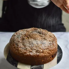 Our baker dusting the Plum & Almond Crumble Cake with powdered sugar just before it goes out. This weekend special is a crowd favourite for its comforting, homely flavour.