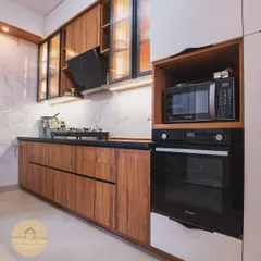 A full view of a contemporary kitchen we designed, featuring built-in appliances for a clean, streamlined look. The combination of wood-finish cabinets, a marble-patterned backsplash, and a black countertop creates a sophisticated and timeless aesthetic.