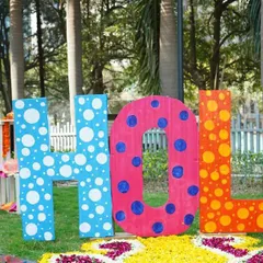 Large, custom props are perfect for photo opportunities and brand visibility. These oversized, polka-dotted "HOLI" letters provided a fun, interactive centerpiece for an outdoor corporate celebration, surrounded by a bed of flower petals.