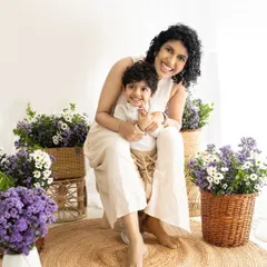 A joyful 'Mom and Son' portrait in a beautiful, light-filled studio setup with purple and white flowers.