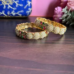 Our delicate pearl bangle collection. This pair features clusters of pearls alternating with small floral motifs made of red and green stones.