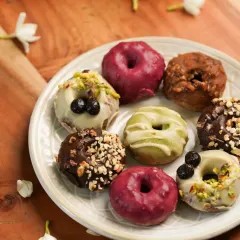 A plate of assorted, beautifully decorated mini doughnuts. The variety of colors and toppings makes this a fun and tempting image.