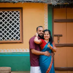 A happy and intimate portrait of a couple in traditional wear. The colorful, rustic house in the background adds a charming and authentic touch to this pre-wedding photo.