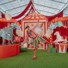 The circus comes to life with interactive performers and life-sized animal props. Here, a friendly clown welcomes guests to the main stage, complete with a custom-built elephant and carousel horse, creating an atmosphere of playful wonder.