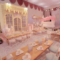 An overview of the Parisian fairytale dining area, featuring a custom patisserie, a carousel, and an inflatable castle. The entire room is unified by a soft pink and pastel color palette.