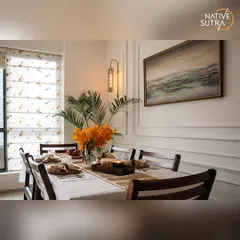 A side view of the dining setup, showing the elegant Roman blinds that filter natural light beautifully. The combination of dark wood chairs, a crisp white tablecloth, and warm lighting creates an intimate and refined dining experience.