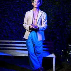 A full-length shot from a fashion show, showcasing a complete designer look. The moody, blue-toned lighting creates a unique atmosphere that elevates the image beyond standard runway documentation into something more conceptual.