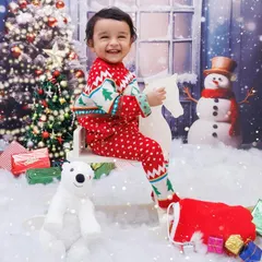 A joyful toddler in a Christmas sweater rides a rocking horse in a snowy, magical setting.
