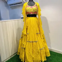 This bright yellow tiered lehenga comes with a modern twist, featuring a heavily embroidered blouse and a matching jacket with pearl detailing along the edges. It's a fun and stylish option for a Haldi function.