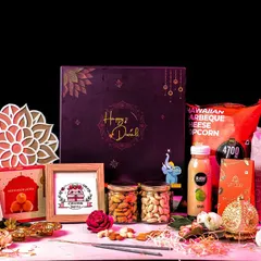 This premium Diwali gift set is perfect for making a grand impression. It features a large "Happy Diwali" gift box, gourmet popcorn, cookies, a healthy drink, dry fruits, and decorative items, all presented on a bed of festive pink filler.