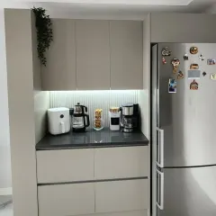 A wider view of the pantry and coffee station, showing its seamless integration next to the refrigerator. The consistent design language creates a cohesive and organized look in the kitchen area.