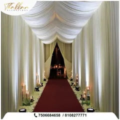 A simple yet incredibly elegant entrance. I used flowing white drapes to create a tunnel effect, with a red carpet and large candles lining the path for a dramatic and sophisticated welcome.