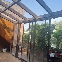 This angle shows how our glass extension integrates with the home's interior, featuring wood-paneled walls and a seamless transition. The transparent roof and walls make the space feel expansive and bright.