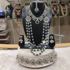 A perfect choice for a modern reception look, this diamond and emerald look-alike set offers breathtaking sparkle. It includes a layered haram, a matching choker, earrings, and a maang tikka, all designed to make a statement.