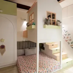 I designed this custom house-shaped bunk bed to make the most of a small room. It creates a cozy sleeping area below and a fun play loft above, with pastel-colored stairs that double as storage drawers.