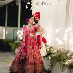 A fairytale moment brought to life. The bride's magnificent red lehenga and the groom's elegant sherwani create a stunning portrait against a backdrop of warm, festive lights, showcasing our expertise in capturing grand North Indian weddings.