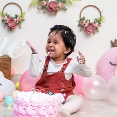 Every child reacts differently, and we are there to capture their unique personality. This little one is having a blast, with hands full of cake and a smile that lights up the room during her first birthday photoshoot.