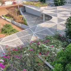 An aerial view of the completed Talaricheruvu Rural School, showing how the geometric bamboo canopy flows over the landscape. The rooftop is covered in bougainvillea, integrating the building with its natural surroundings.