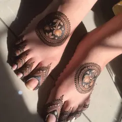 A modern and stylish foot mehandi featuring a central floral mandala and detailed designs on the toes. This is great for someone who wants a less traditional look.