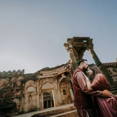 A low-angle, wide shot that emphasizes the scale of the ancient ruins. The couple shares a tender moment, creating a beautiful contrast between enduring love and timeless architecture.