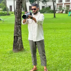 A candid shot of me at work, camera in hand, in a lush outdoor setting.