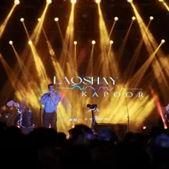 Laqshya Kapoor performing under dramatic golden spotlights at IMS-BHU. This wide shot shows the impressive stage production of a top-tier college festival.
