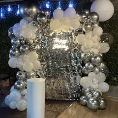 Here is another look at the silver and white shimmer wall setup, this time with fairy lights twinkling in the background. The combination of the reflective sequins and the soft lights makes for an absolutely dreamy and festive atmosphere.