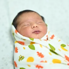 A serene close-up of a sleeping newborn, peacefully swaddled. Capturing these quiet, beautiful details is just as important as capturing the big celebration moments.
