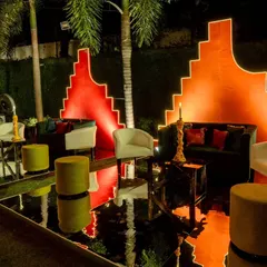 A futuristic lounge area with a bold color palette. We used black mirrored floors to reflect the glowing orange geometric backdrops, creating a sleek and vibrant space for guests.