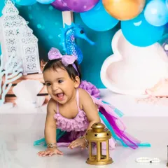 A mermaid's joyful laugh. This little one is having a wonderful time exploring our under-the-sea world, complete with colorful props and balloons.