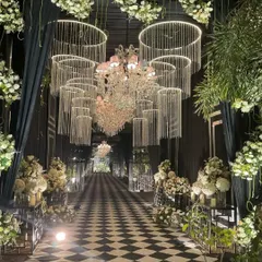 Your journey begins with a grand entrance. I love designing stunning passages like this modern black and white checkered aisle, framed by dramatic crystal chandeliers, to set a tone of sophisticated glamour from the very first step.