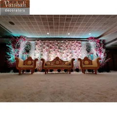 We can create a full wall of flowers as a lush and romantic backdrop for your reception stage. This design uses a mix of pink and white flowers with elegant diwan seating.