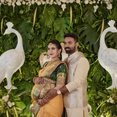 The happy couple posing in front of the decor I designed for their baby shower. The green wall with white peacocks provided a fresh and elegant setting for their celebration.