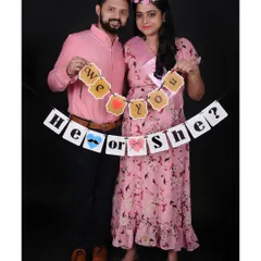 A fun gender reveal photo with a "He or She?" banner. These couple maternity sessions are a wonderful way to capture the anticipation and joy together.