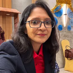 A selfie of me in a red and black suit. At 26, on my first international work trip, I was made project lead over a more experienced male colleague who couldn't handle it. I learned then to focus on my work and impact, not the resistance of others.