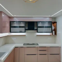 A beautiful modular kitchen in a soft rose-gold or onion pink color. The design includes frosted glass upper cabinets and under-cabinet lighting for a warm, inviting glow.
