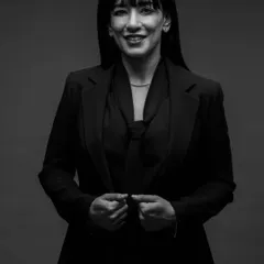 A classic black and white headshot that exudes professionalism. The lighting is crafted to be flattering yet strong, highlighting her expression and creating a timeless image for her brand.