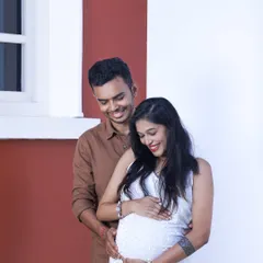 A tender moment between an expecting couple during their outdoor shoot. The father-to-be gently holds the baby bump, sharing a smile with his partner.