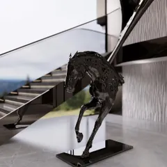 A close-up of the glossy black horse sculpture at the foot of the Meraki staircase. The sculpture's fluid, powerful lines echo the dynamic form of the staircase itself, creating a perfect pairing of art and architecture.