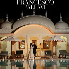A breathtaking portrait of the couple against the stunning architecture of a palace venue at night. This shot combines romance with the grandeur of a destination wedding, reflecting in the calm pool waters.