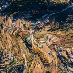 This high-altitude drone photo reveals the terraced farming and winding roads of the hills surrounding Naukuchiatal. It showcases the patterns of human settlement within the vast natural landscape of the Kumaon region.