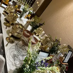 A long shot of an elegant buffet line ready for a house party. The setup includes our signature gold serving dishes, beautiful floral arrangements, and ambient lighting to create a sophisticated dining experience at home.