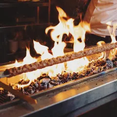 The heart of my Turkish kitchen. Here, a massive Adana kebab is grilled over open flames, a testament to our commitment to authentic cooking methods and bold flavors.