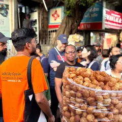 Our guide leads a group past a street vendor selling a mountain of golgappas. We help you navigate the bustling market to find the most delicious and hygienic street food stalls.