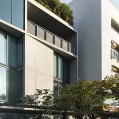 A detail of the facade of our studio, showing the relationship between the concrete structure, large glass panels, and the rooftop greenery. The building is designed to be an active participant in its street context.