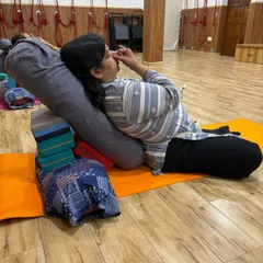 This close-up shows a student practicing pranayama while her body is fully supported by bolsters and blocks. This practice is excellent for managing stress and improving respiratory function.